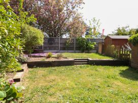 A garden with grass lawn steps plants a wooden shed and a wooden fence at Sweetacres in Hemsby