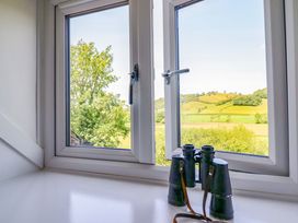 A window with binoculars overlooking a countryside view at Upper Dolarddyn in Castle Caereinion