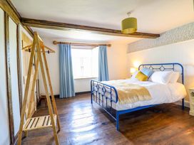 A bedroom with a blue bed and wooden flooring at Upper Dolarddyn in Castle Caereinion