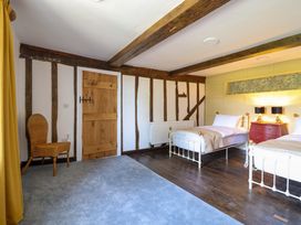 A bedroom with two beds and a chair at Upper Dolarddyn in Castle Caereinion