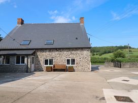 A house with a bench and planters outside at Upper Dolarddyn in Castle Caereinion