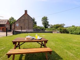 A garden with a wooden table and drinks at Upper Dolarddyn in Castle Caereinion