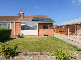 A single story brick house with solar panels on the roof and a lawn in front at Hendre in Pensarn