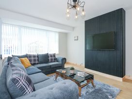 A living room with a sectional sofa a coffee table a mounted television and vertical blinds at Hendre in Pensarn
