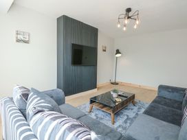 A living room with grey sofas a black marble coffee table a floor lamp and a wall mounted television at Hendre in Pensarn