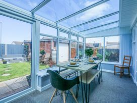 A dining area with a table set for four and large windows opening to a garden at Hendre in Pensarn