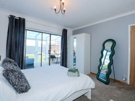 A bedroom with a bed cushions wardrobe and a large wavy standing mirror at Hendre in Pensarn