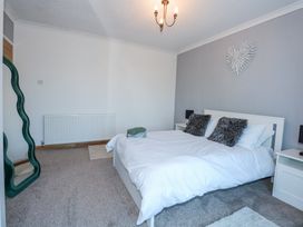 A bedroom with a double bed two nightstands a decorative wall piece and a standing mirror at Hendre Pensarn