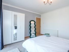 A bedroom with a white wardrobe a wavy green standing mirror and a bed with folded towels at Hendre in Pensarn