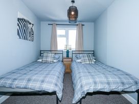 A bedroom with two single beds with blue plaid bedding a small wooden nightstand a lamp beige curtains and a zebra picture on the wall at Hendre in Pensarn