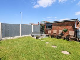 A backyard with a lawn seating area and chairs along a brick wall at Hendre in Pensarn
