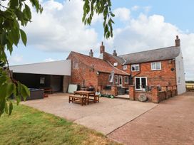 An outdoor patio area with brick buildings picnic benches a covered seating area and garden in the background at Bewholme Skipsea