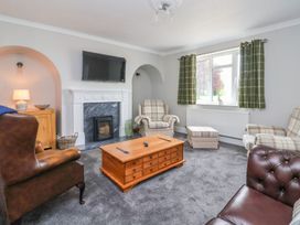 A living room with armchairs a wooden coffee table a fireplace and a TV above it at Bewholme in Skipsea