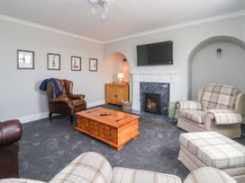 A living room with armchairs a wooden coffee table a fireplace and a television at Bewholme in Skipsea