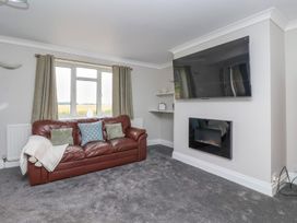 A living room with a brown leather sofa and a wall mounted television above a fireplace at Bewholme in Skipsea