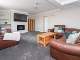A living room with brown leather sofas a wooden coffee table a wall-mounted television and a fireplace at Bewholme in Skipsea