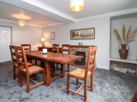 A dining room with a wooden table and six chairs a lamp a vase with dried plants and a fireplace at Bewholme in Skipsea