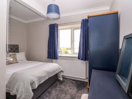 A bedroom with a bed next to a window with blue curtains and a blue wardrobe at Bewholme in Skipsea