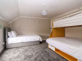 A bedroom with a single bed and wooden bunk bed on a grey carpet floor at Bewholme in Skipsea