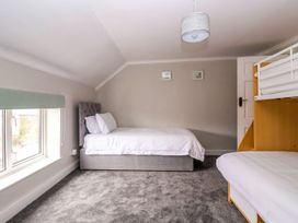 A bedroom with a double bed a bunk bed a window and carpeted floor at Bewholme in Skipsea