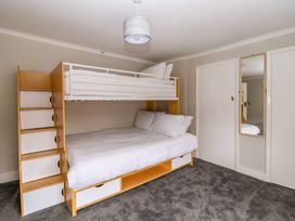 A bedroom with a bunk bed with white bedding a wall mirror and carpet flooring at Bewholme in Skipsea