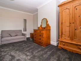 A room with a gray sofa a wooden dresser with a mirror and a wooden wardrobe at Bewholme in Skipsea