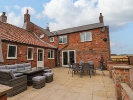 A patio area with outdoor seating and dining furniture outside a brick house at Bewholme in Skipsea