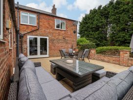 An outdoor patio with a cushioned wicker sofa set and dining table with chairs at Bewholme in Skipsea