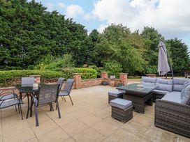 An outdoor patio with a glass table and chairs and a cushioned sectional sofa with a table at Bewholme in Skipsea