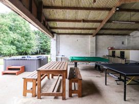 An open space with wooden table and benches hot tub pool table ping pong table and bar area at Bewholme in Skipsea