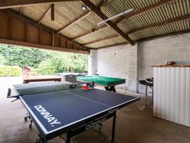 A covered area with a ping pong table, a covered pool table, stools, and a counter at Bewholme in Skipsea