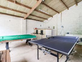 A game room with a ping pong table a covered pool table a bar with stools and white brick walls at Bewholme in Skipsea