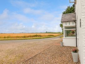 A view of a gravel driveway beside a white house with plants in pots and a field in the background at Bewholme in Skipsea