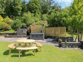 A garden with a hot tub and an outdoor table at Coytrahen House in Coytrahen near Bettws