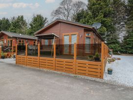 A wooden cabin with a glass and wood fenced porch and a swing in front at Lodge 2 in Auchterarder