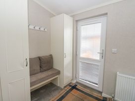 An entryway with a cushioned bench between two cabinets a wall-mounted coat rack and a door with blinds at Lodge 2 in Auchterarder
