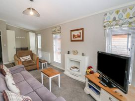 A living room with a sofa armchair coffee table television and fireplace at Lodge 2 in Auchterarder