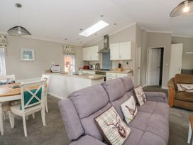 An open plan living room and kitchen with sofas dining table and kitchen cabinets at Lodge 2 in Auchterarder