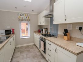 A kitchen with cabinets a microwave a stove and a window with blinds at Lodge 2 in Auchterarder