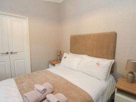 A bedroom with a bed with beige headboard white pillows with butterfly designs beige throw blanket bedside tables with lamps and folded towels at Lodge 2 in Auchterarder
