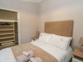 A bedroom with a double bed brown headboard bedside tables with lamps and open closet shelves at Lodge 2 in Auchterarder