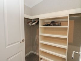 A walk-in closet with white shelves and hanging rods with hangers at Lodge 2 in Auchterarder
