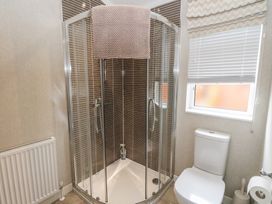 A bathroom with a corner shower enclosure a toilet a window with blinds and a radiator at Lodge 2 in Auchterarder