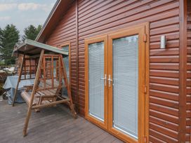 A wooden porch swing next to glass doors with blinds at Lodge 2 in Auchterarder