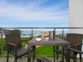 A balcony with a table and chairs overlooking the sea at Far Cliffs in St. Ives
