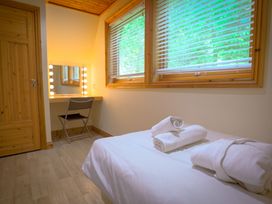 A bedroom with towels on a bed and a vanity mirror at Lodge 68 - Fern Gully near Finlakes Holiday Park