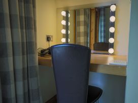 A dressing area with a mirror and chair at Lodge 68 - Fern Gully near Chudleigh