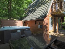 An outdoor area with a hot tub and wooden cabin at Lodge 68 - Fern Gully near Finlakes Holiday Park