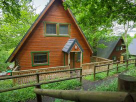 A wooden lodge with a deck and pathway at Lodge 68 - Fern Gully near Finlakes Holiday Park near Chudleigh