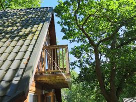 A balcony and roof of a wooden structure surrounded by trees at Lodge 68 - Fern Gully near Finlakes Holiday Park